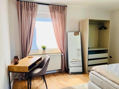 ビュッケブルクにあるCozyHomeの机とベッドと窓のある寝室