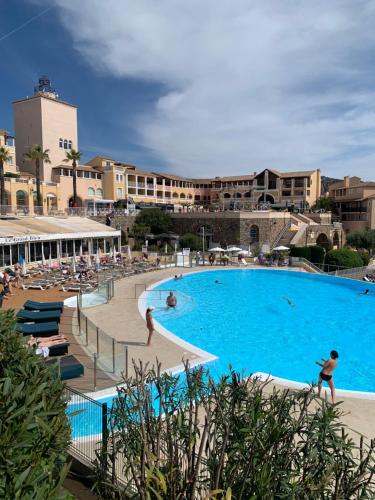 une grande piscine avec des gens dans un complexe hôtelier dans l'établissement Club multisports inclus Piscine chauffée jusqu'au 02 Novembre,CAP ESTÉREL Appartement Très spacieux en REZ de JARDIN, à Saint-Raphaël