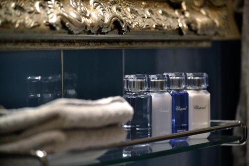 a shelf with four bottles of soap and towels at Hotel Adriatica in Geneva
