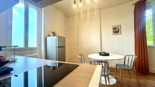 Il comprend une cuisine équipée d'un réfrigérateur, d'une table et de chaises. dans l'établissement L'Écrin Sévigné - Wi-Fi & Near Train Station, à Valence