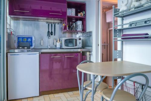 une cuisine avec des armoires violettes et une table avec des chaises dans l'établissement Petit appartement 20m2 - 2-4 personnes - Quartier Bel Air, à Les Sables-dʼOlonne