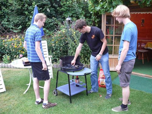a group of three men standing around a grill at "Haus Burck" Modern retreat in Wankendorf