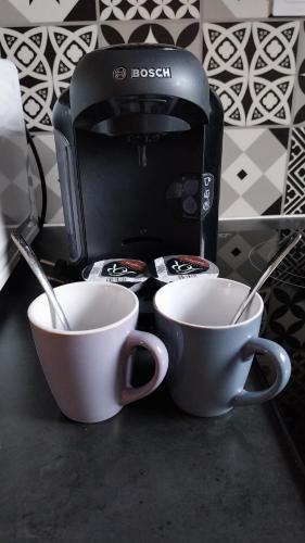deux tasses sur un comptoir à côté d'une cafetière dans l'établissement Maisonnette cocoon proche de l'aéroport d'Orly, à Paray-Vieille-Poste