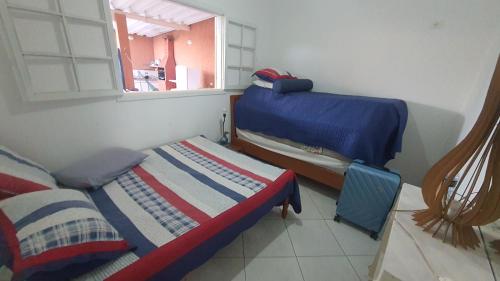a small room with two beds and a window at casa do Pedro in Guarujá