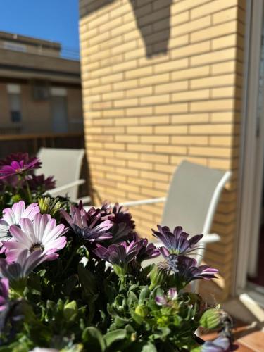 a table with purple flowers and chairs on a patio at Casa vacanza Torvaianica a due passi dal mare in Torvaianica