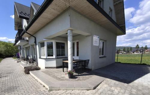 a building with a porch with a table and chairs at Apartaments Gory in Niedzica Zamek