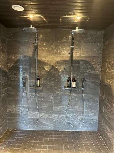 a shower in a bathroom with two shower heads at Huvilarannalla in Sotkamo