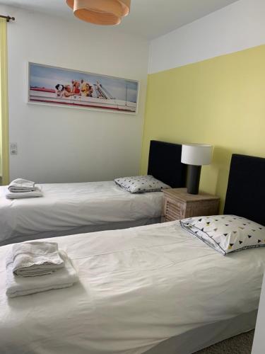 une chambre avec deux lits et un tableau au mur dans l'établissement Appartement hyper centre avec jardin, à Dinard