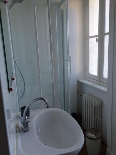 une salle de bain blanche avec un lavabo et une fenêtre dans l'établissement Appartement hyper centre avec jardin, à Dinard