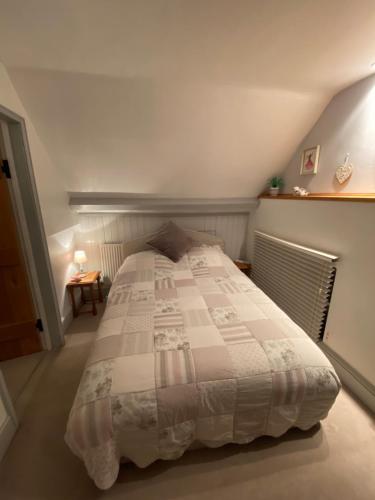 ein Schlafzimmer mit einem großen Bett im Dachgeschoss in der Unterkunft St Catherines Cottage The Old Schoolhouse in Long Melford