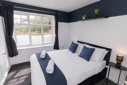 a bedroom with a bed with blue walls and a window at Boutique 2-Bed Apartment in Wolverhampton Centre in Wolverhampton