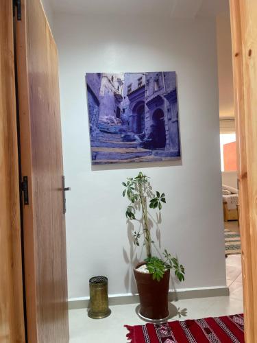 a room with a potted plant and a painting on the wall at Tamraght Bleu House in Tamraght Oufella