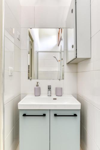 une salle de bain blanche avec un lavabo et un miroir dans l'établissement Appartement T2 rez-de-chaussée Plage du Grazel, à Gruissan