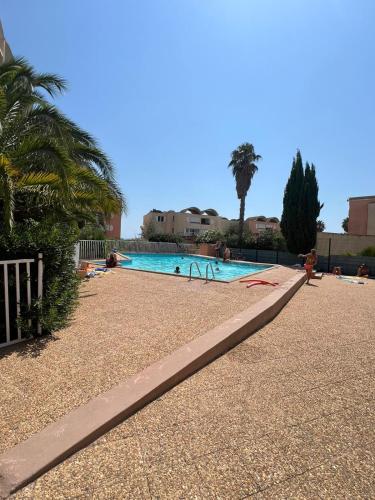 - une piscine bordée de palmiers dans l'établissement Appartement T2 rez-de-chaussée Plage du Grazel, à Gruissan