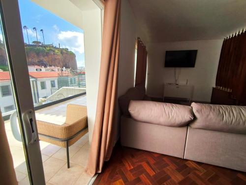 a living room with a couch and a balcony at Villa Supranee Relaxation in Câmara de Lobos