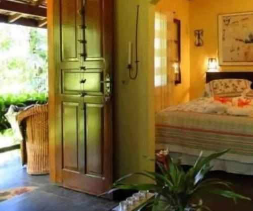 a bedroom with a door leading to a bed at Pousada Romântica Serra da Mata in Penedo
