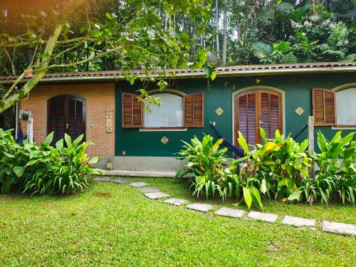 a green house with windows and plants in front of it at Pousada Romântica Serra da Mata in Penedo