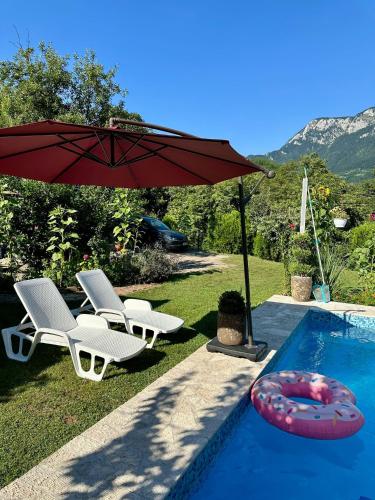 a red umbrella and chairs next to a swimming pool at Guest House Queen in Konjic