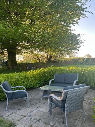 twee stoelen en een tafel en een bank op een patio bij Winstitchen Cottage situated near the River Barle in Simonsbath