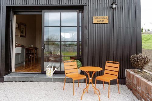 a table and three chairs sitting in front of a building at Fisherman's Lodge at Angliham Estate in Kilroghter