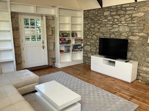 a living room with a tv on a stone wall at Lovely cottage in Penryn centre with parking in Penryn