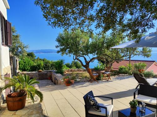 patio z krzesłami, parasolem i oceanem w obiekcie Weekend house Olive garden w mieście Donje Selo na Šolti