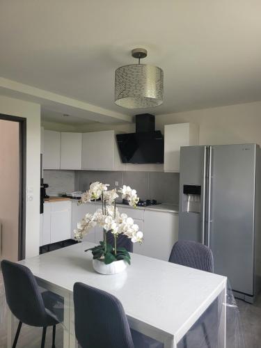 - une cuisine avec une table blanche et des fleurs dans l'établissement Maison calme et moderne, à Engenville