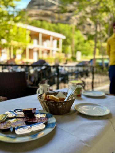 a table with plates and a basket of food on it at Mpoufidis Rock House Meteora in Kalabaka