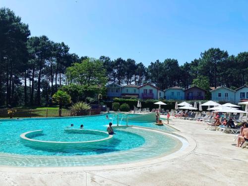 une grande piscine avec des gens dans l'eau dans l'établissement Maison à Lacanau Océan avec piscine, proche océan, lac, golf, à Lacanau