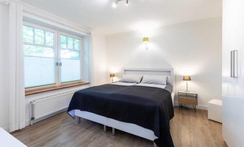 a white bedroom with a bed and a window at Hygge 13 in Nortorf