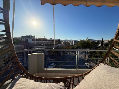 a hammock on a balcony with a view of a parking lot at Sunny Home Private Jacuzzi Hydromassage, Fireplace, Acropolis & Lycabettus View, Underground Parking, 300m Metro Peristeri in Athens