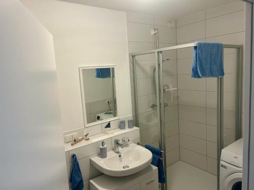 a white bathroom with a sink and a shower at Ferienwohnung Moin in Bremerhaven