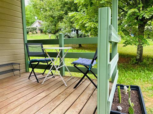 une terrasse couverte avec 2 chaises et une table. dans l'établissement Chalet cosy au cœur de la nature, à Lissac-sur-Couze