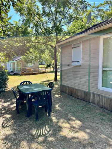 - une table de pique-nique et des chaises en face d'une maison dans l'établissement Chalet cosy au cœur de la nature, à Lissac-sur-Couze