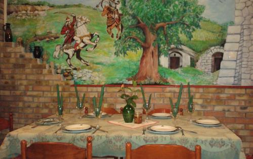 a table with chairs and a painting on the wall at Kisdiófa Panzió és Vendéglő in Vajdácska