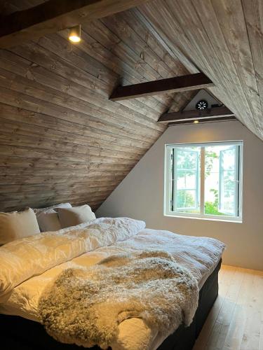 a bed in a room with a wooden ceiling at Traditional Scanian Farm In The Fields Of Österlen in Gärsnäs