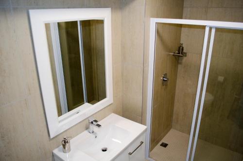 Un baño con lavabo y ducha con espejo. en Mayfair Luxury Apartments, en Ciudad del Cabo
