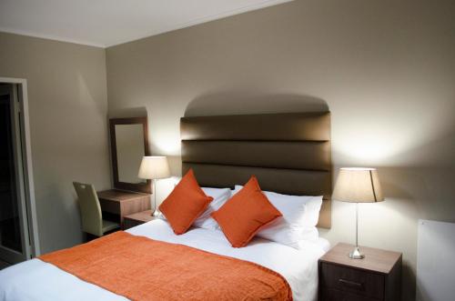 Un dormitorio con una cama con almohadas naranjas y blancas. en Mayfair Luxury Apartments, en Ciudad del Cabo