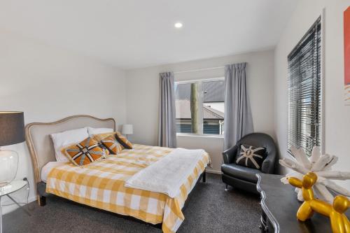 a bedroom with a bed and a chair and a window at Central City Comfort and Style in Christchurch