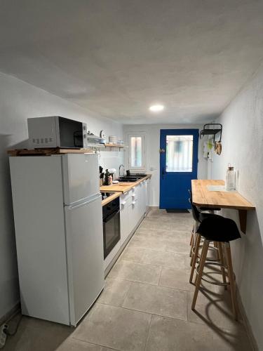 - une cuisine avec des appareils blancs et une porte bleue dans l'établissement Maison cosy idéal couple 10 min mer & montagne, à Saint-André