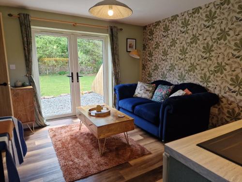 a living room with a blue couch and a table at The Stables by Blake View Holidays, comprising The Nest, The Drey, The Burrow and the Den, 3 miles from Ennerdale in Rowrah