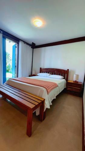 a bedroom with a large bed and a bench at Sun House Manguinhos in Búzios