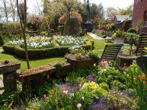 a garden with flowers and tables and benches at Hundred House Hotel in Ironbridge
