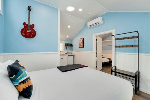 a bedroom with a white bed and a guitar on the wall at Riverside Colorado in Bellvue