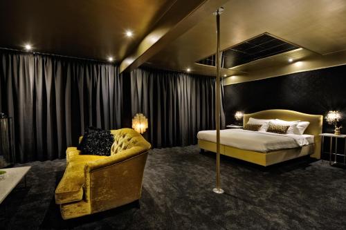 a bedroom with a bed and a yellow chair at Van der Valk Hotel Sassenheim - Leiden in Sassenheim