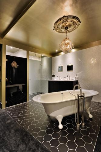 a bath tub in a bathroom with a chandelier at Van der Valk Hotel Sassenheim - Leiden in Sassenheim