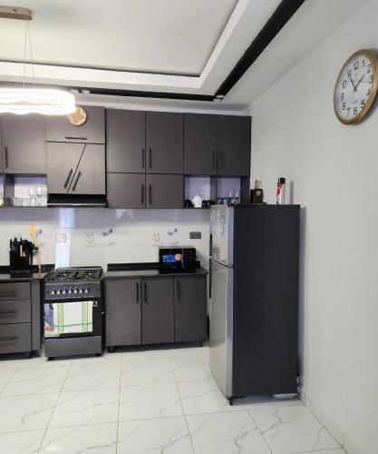 a kitchen with a refrigerator and a clock on the wall at Cozy Luxe 2 Bedroom 2 Bath Apartment with Balcony BBB NATION OASIS KIGALI in Kigali