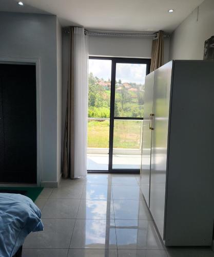 a bedroom with a large sliding glass door with a view at Cozy Luxe 2 Bedroom 2 Bath Apartment with Balcony BBB NATION OASIS KIGALI in Kigali