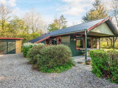 a green house with a garage and some bushes at 4 person holiday home in Toftlund-By Traum in Toftlund