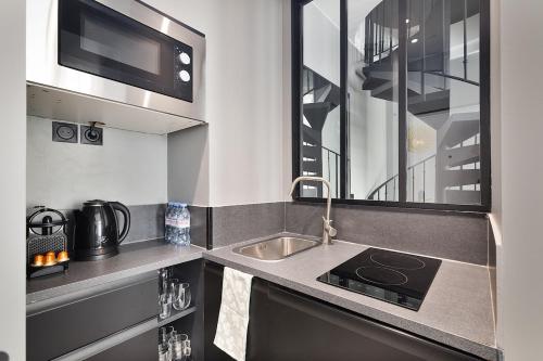 une petite cuisine avec un évier et un micro-ondes dans l'établissement LaSuite Montmartre, à Paris